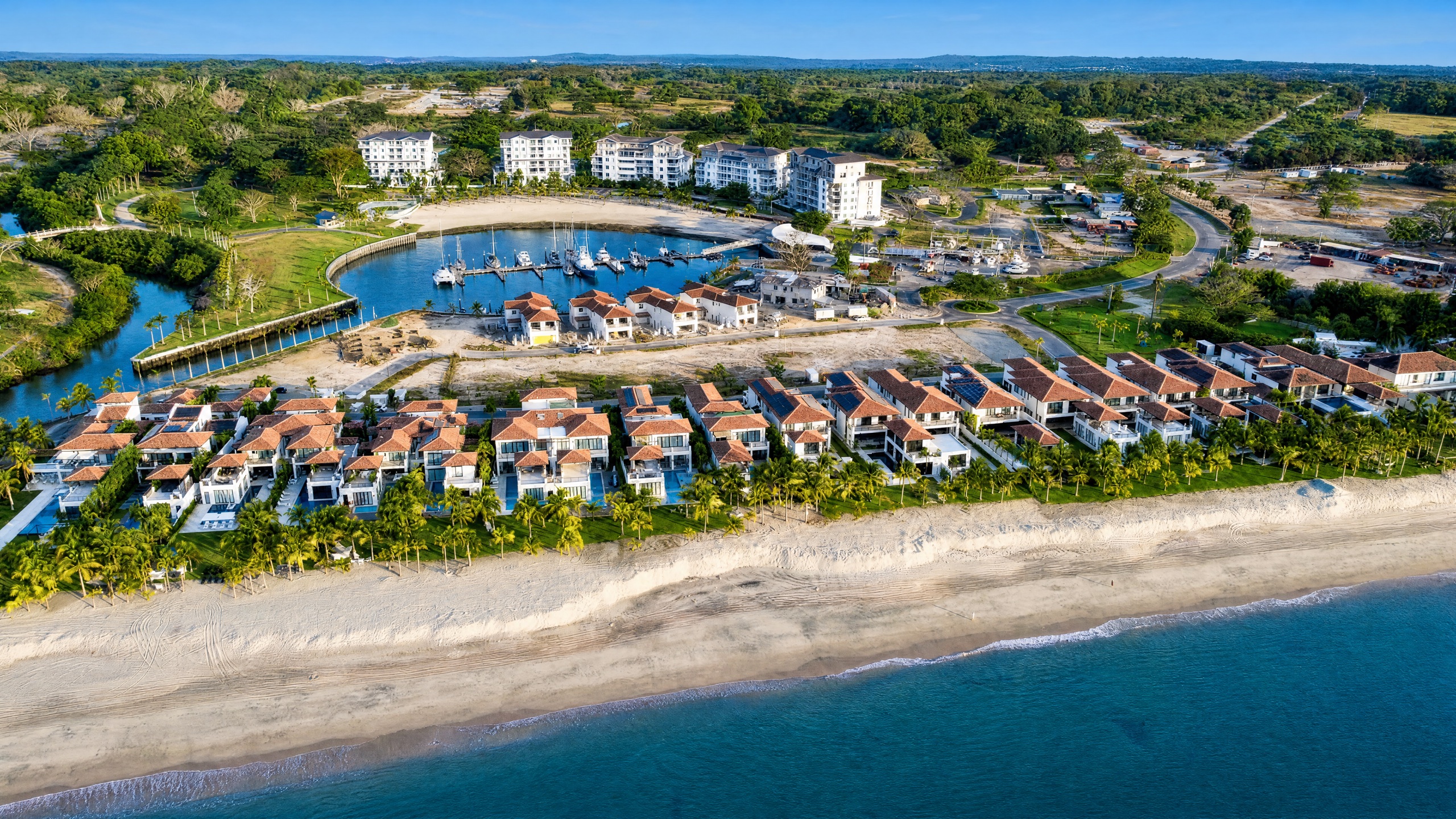 Buenaventura luxury beach resort community on the Pacific coast of Panama, branded low-rise residences and villas beside a golf course and tan-sand beach at golden hour.